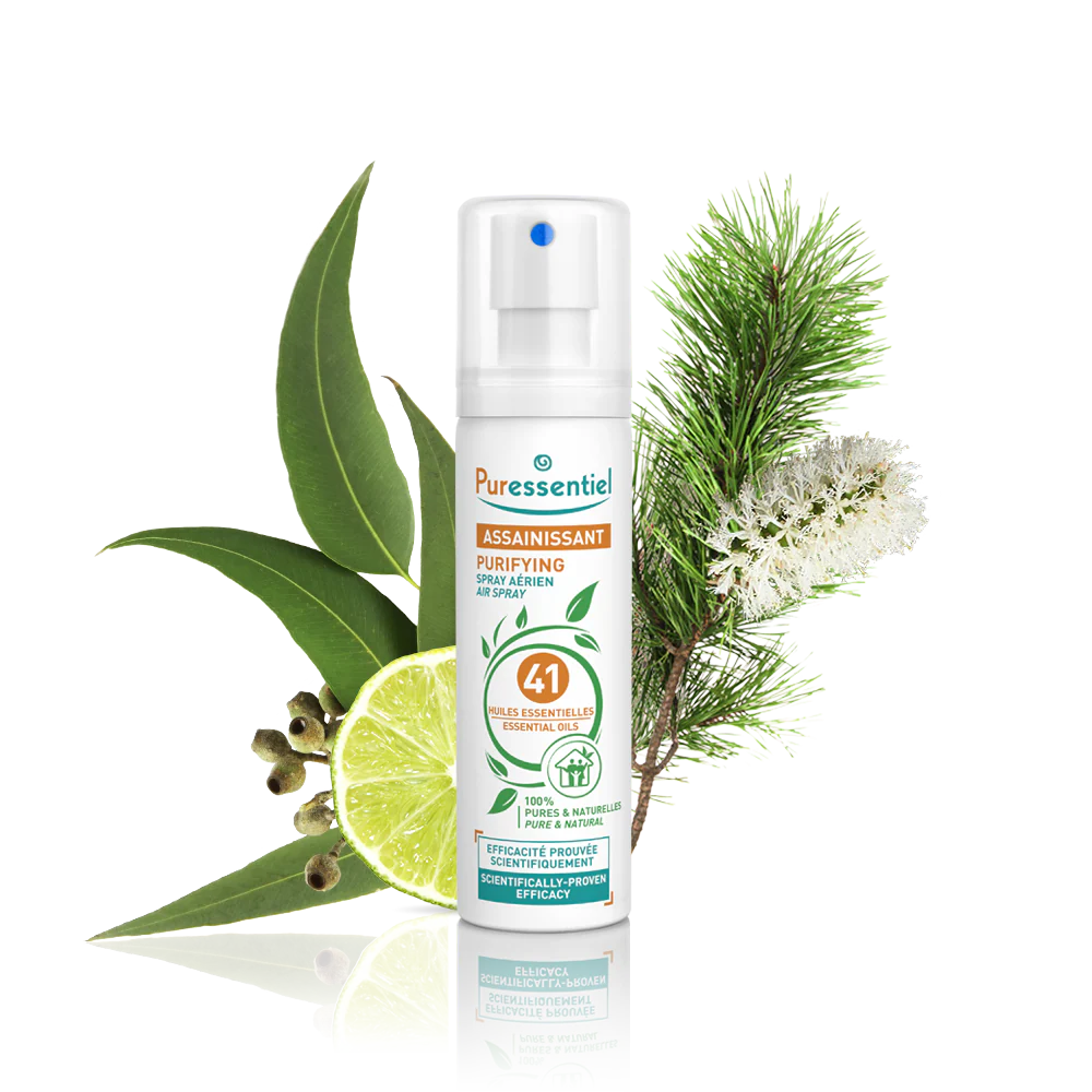 Puressentiel purifying air spray bottle surrounded by eucalyptus leaves, lime, and pine.
