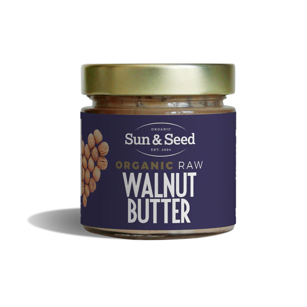 Small glass jar of Sun & Seed Organic Raw Walnut Butter featuring a gold lid and a dark purple label with a walnut heart graphic.