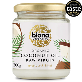 A jar of Biona Organic Raw Virgin Coconut Oil with a gold lid and tropical design, featuring palm leaves and coconut imagery. It has a "Great Taste 2024" award badge.