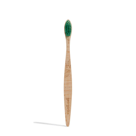 Wooden toothbrush with green bristles and engraved leaf pattern on the handle. The word "georganics" is etched into the handle, conveying an eco-friendly feel.