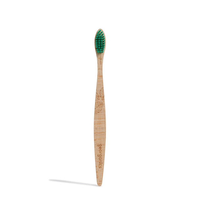 Wooden toothbrush with green bristles and engraved leaf pattern on the handle. The word "georganics" is etched into the handle, conveying an eco-friendly feel.