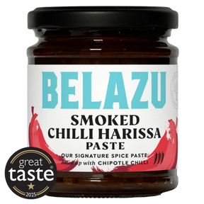 A jar of Belazu Smoked Chilli Harissa Paste on a white background, featuring a black lid, dark brown glass, and a white label with turquoise and red text and chili graphics. A circular 'great taste 2025' badge is overlaid in the bottom-left corner.