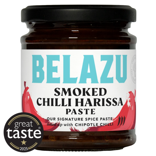 A jar of Belazu Smoked Chilli Harissa Paste on a white background, featuring a black lid, dark brown glass, and a white label with turquoise and red text and chili graphics. A circular 'great taste 2025' badge is overlaid in the bottom-left corner.