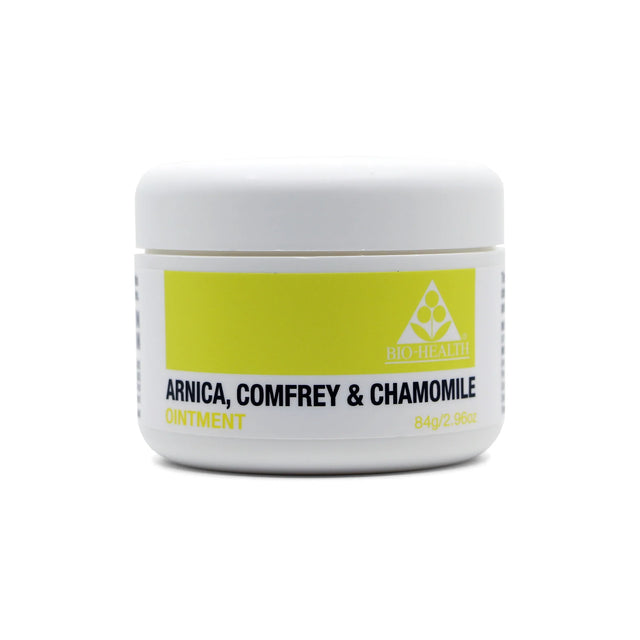 A small white plastic jar of Bio-Health ointment with a yellow and white label featuring the text "Arnica, Comfrey & Chamomile Ointment" and a triangular logo.