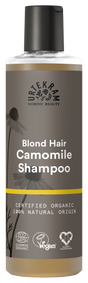A tall bottle of Urtekram Camomile Shampoo for blond hair with a grey and brown label featuring camomile flower illustrations and a thin yellow horizontal stripe. The label indicates it is certified organic, 100% natural origin, and carries Vegan and Ecocert COSMOS Organic certifications.