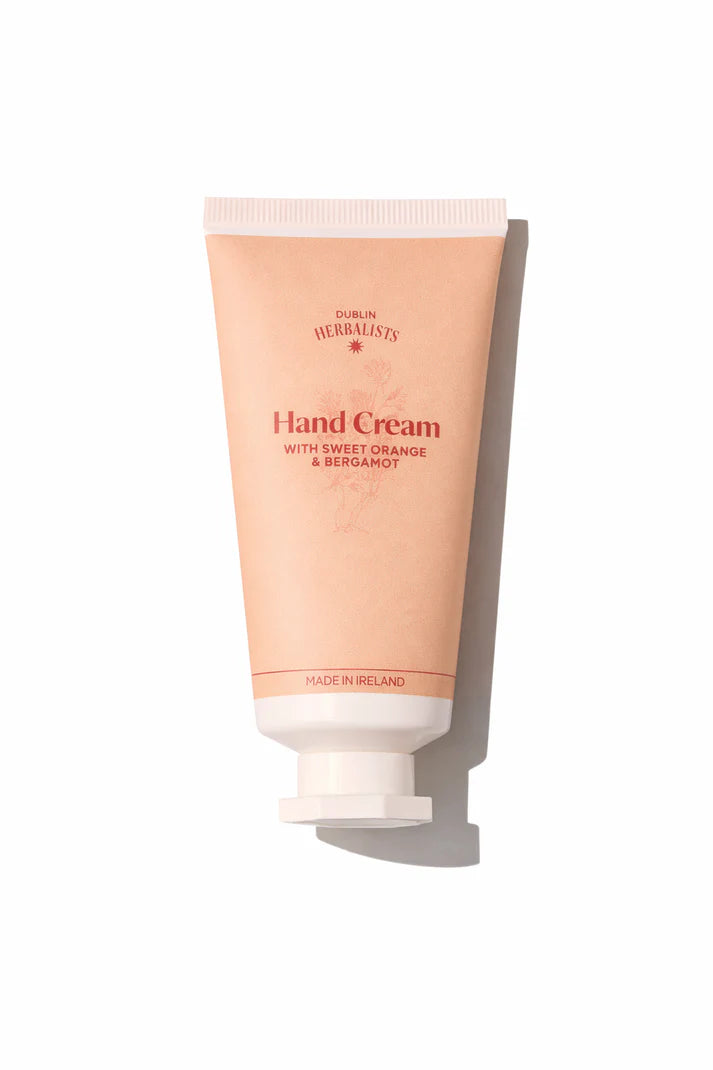 A peach-colored tube of Dublin Herbalists Hand Cream with Sweet Orange and Bergamot.
