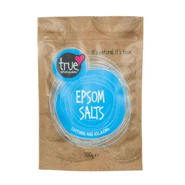 A 500g brown paper pouch of True Epsom Salts featuring a bright blue circular label with white line art and bowl illustrations.