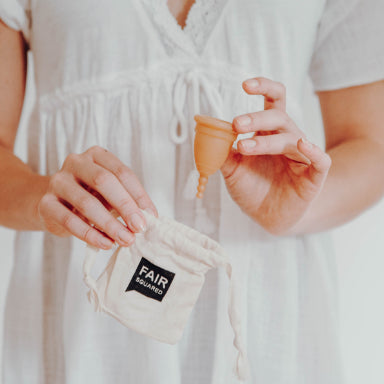 Fair Squared Period Cup made from Fair Trade natural rubber, shown with its organic cotton storage bag.