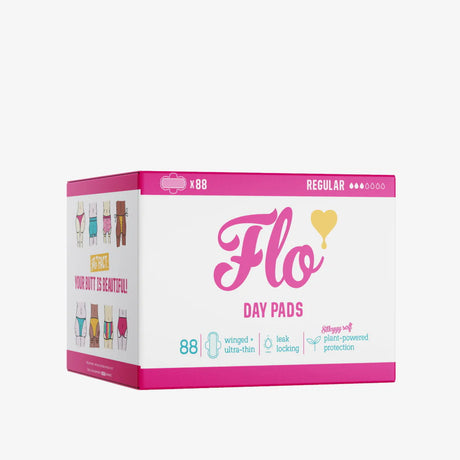 Box of Flo Day Pads with pink accents, featuring "88 regular" pads. Includes colorful illustrations, heart icon, and a positive message about beauty.