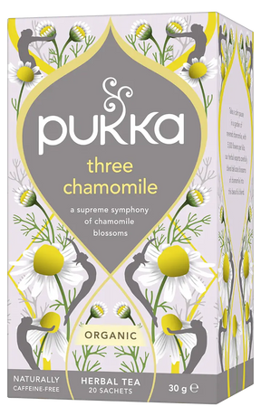 A light purple box of Pukka Organic Three Chamomile herbal tea, featuring a caffeine-free blend of chamomile blossoms containing 20 sachets.