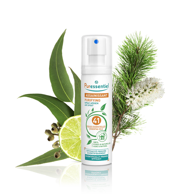 Puressentiel purifying air spray bottle surrounded by eucalyptus leaves, lime, and pine.