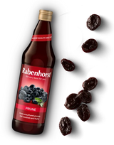 Glass bottle of Rabenhorst Prune juice with a red label, accompanied by scattered dried prunes.