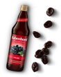 Glass bottle of Rabenhorst Prune juice with a red label, accompanied by scattered dried prunes.