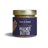Small glass jar of Sun & Seed Organic Raw Walnut Butter featuring a gold lid and a dark purple label with a walnut heart graphic.