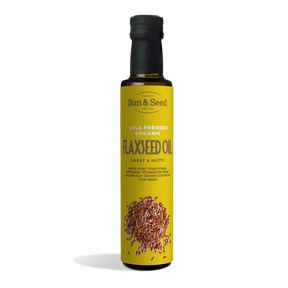 Tall dark glass bottle of Sun & Seed Cold Pressed Organic Flaxseed Oil featuring a bright yellow label with an illustration of flaxseeds at the bottom.