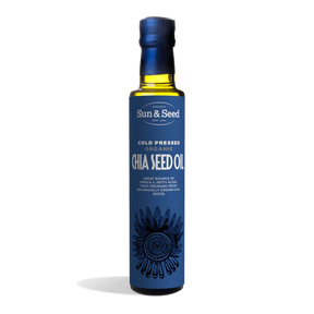 Tall dark glass bottle of Sun & Seed Cold Pressed Organic Chia Seed Oil featuring a deep blue label with an intricate feathered circular graphic at the bottom.