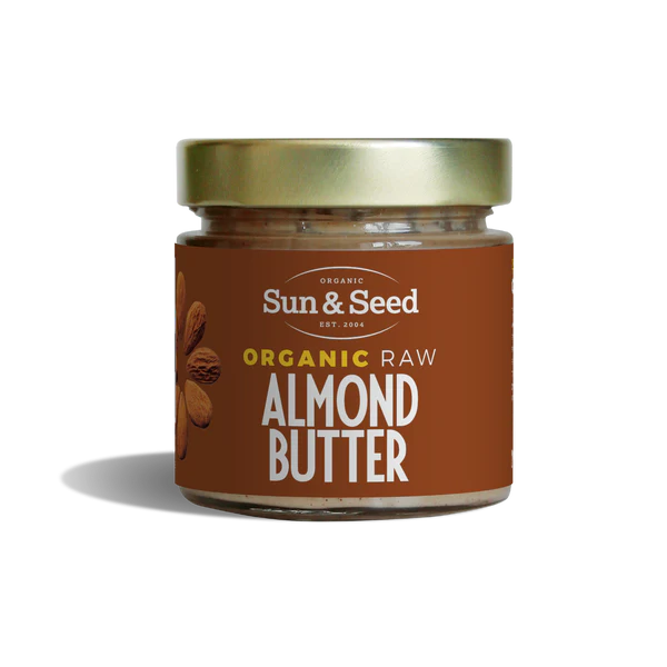 Small glass jar of Sun & Seed Organic Raw Almond Butter featuring a gold lid and brown label.