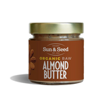 Small glass jar of Sun & Seed Organic Raw Almond Butter featuring a gold lid and brown label.