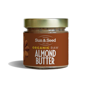 Small glass jar of Sun & Seed Organic Raw Almond Butter featuring a gold lid and brown label.