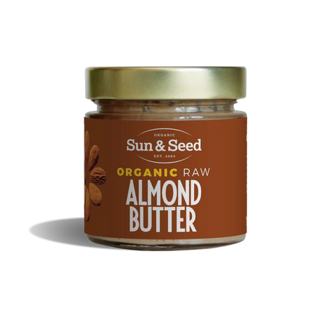 Small glass jar of Sun & Seed Organic Raw Almond Butter featuring a gold lid and brown label.