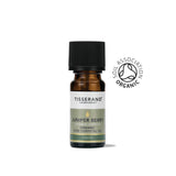 A small amber glass bottle of Tisserand Juniper Berry organic pure essential oil with a sage green and white label and a black cap.