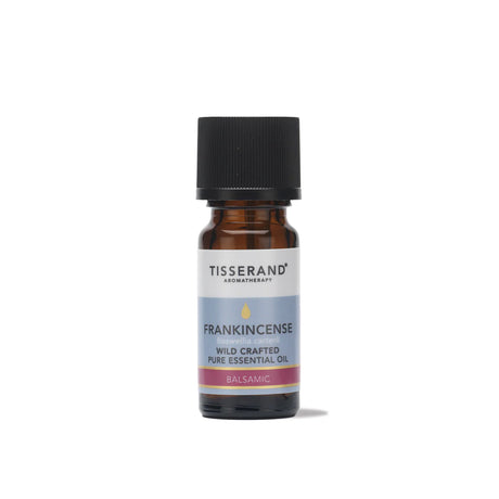 A small amber glass bottle of Tisserand Frankincense wild crafted pure essential oil with a light blue and white label and a black cap.