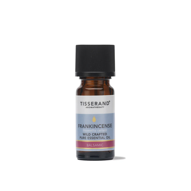 A small amber glass bottle of Tisserand Frankincense wild crafted pure essential oil with a light blue and white label and a black cap.
