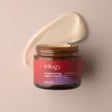 An open amber glass jar of Trilogy Replenishing Night Cream, with a thick smear of the creamy white moisturizer visible behind it.