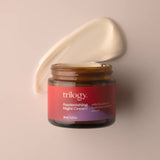 An open amber glass jar of Trilogy Replenishing Night Cream, with a thick smear of the creamy white moisturizer visible behind it.