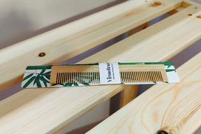 VirtueBrush sustainable bamboo pocket comb on a light wooden slatted surface.