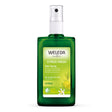 A green glass spray bottle of Weleda Citrus Fresh Deo Spray featuring a light green label with illustrations of lemon slices and a white blossom, labeled as containing no aluminium salts.