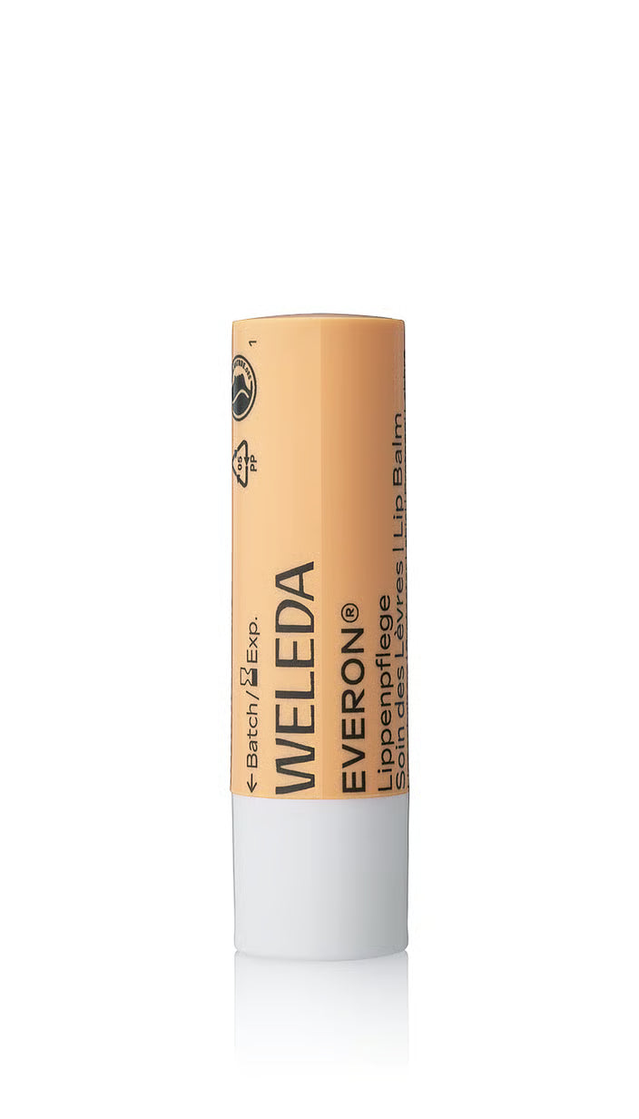 A closed tube of Weleda Everon Lip Balm standing upright, featuring a peach-colored cap with the brand logo and "Lippenpflege" text over a white base.