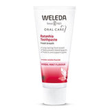 White tube of Weleda Ratanhia Toothpaste with red accents, featuring "Herbal Mint Flavour" and benefits for gums and fresh breath.