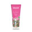 A pink 200ml tube of Weleda Love Shower Cream featuring "Indulging Rose" text and an illustration of a woman in a sun hat carrying a basket of pink roses through a garden.