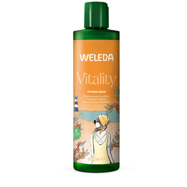 A large 400ml green bottle of Weleda Vitality Shower Cream featuring an orange label with a beach-themed illustration of a woman looking at a lighthouse, surrounded by sea buckthorn plants.
