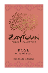 A rectangular soap bar label or package front for Zaytoun From Palestine Rose olive oil soap. The background is a muted dusty rose/coral color with a decorative floral border at the top and bottom, a stylized tree made of leaves and Arabic calligraphy in the center, and black and gold text reading 'ZAYTOUN FROM PALESTINE', 'ROSE', 'olive oil soap', and 'Handmade in Nablus'.