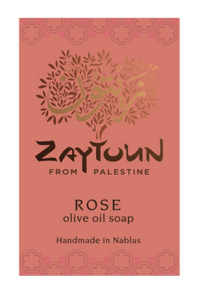 A rectangular soap bar label or package front for Zaytoun From Palestine Rose olive oil soap. The background is a muted dusty rose/coral color with a decorative floral border at the top and bottom, a stylized tree made of leaves and Arabic calligraphy in the center, and black and gold text reading 'ZAYTOUN FROM PALESTINE', 'ROSE', 'olive oil soap', and 'Handmade in Nablus'.