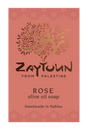 A rectangular soap bar label or package front for Zaytoun From Palestine Rose olive oil soap. The background is a muted dusty rose/coral color with a decorative floral border at the top and bottom, a stylized tree made of leaves and Arabic calligraphy in the center, and black and gold text reading 'ZAYTOUN FROM PALESTINE', 'ROSE', 'olive oil soap', and 'Handmade in Nablus'.
