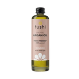 Bottle of Fushi organic argan oil on a light background. Label is soft pink with black text and white flower graphic, conveying a natural, nourishing tone.