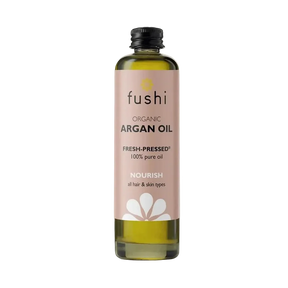 Bottle of Fushi organic argan oil on a light background. Label is soft pink with black text and white flower graphic, conveying a natural, nourishing tone.