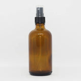 Amber glass spray bottle with a black pump dispenser, designed for versatile use with liquids.