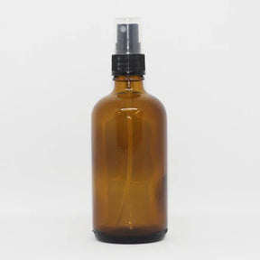 Amber glass spray bottle with a black pump dispenser, designed for versatile use with liquids.